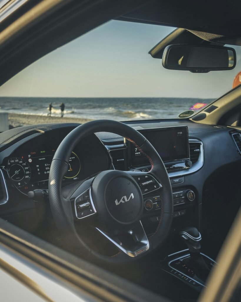 Inside my car, parked by the sea with the dashboard and steering wheel in view